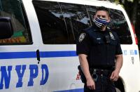 A NYPD police offer wears a Blue Line facemask at the scene of a shooting