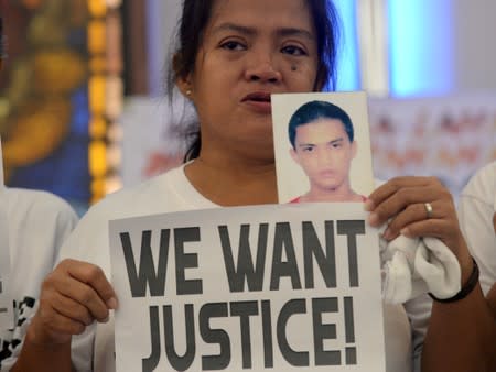 FILE PHOTO: A woman displays a picture of her son, a drug war victim, and a placard during a protest against the war on drugs by President Rodrigo Duterte in Quezon city