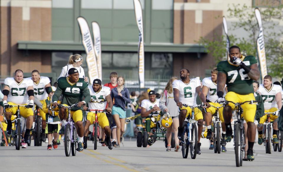 Green Bay Packers players ride bikes to NFL football training camp Monday, July 28, 2014, in Green Bay, Wis. (AP Photo/Morry Gash)