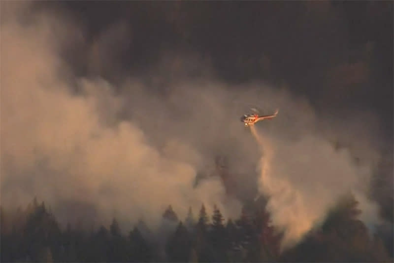 Image: A firefighting helicopter flies over the Estrada Fire in the Santa Cruz area, in California. (KNTV)