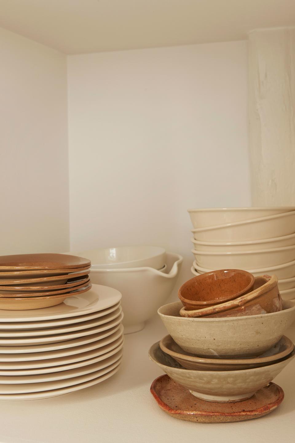 Stacks of cream porcelain by HAY sit with glazed clay plates and a variety of antique bowls collected from the Feiffers’ travels.