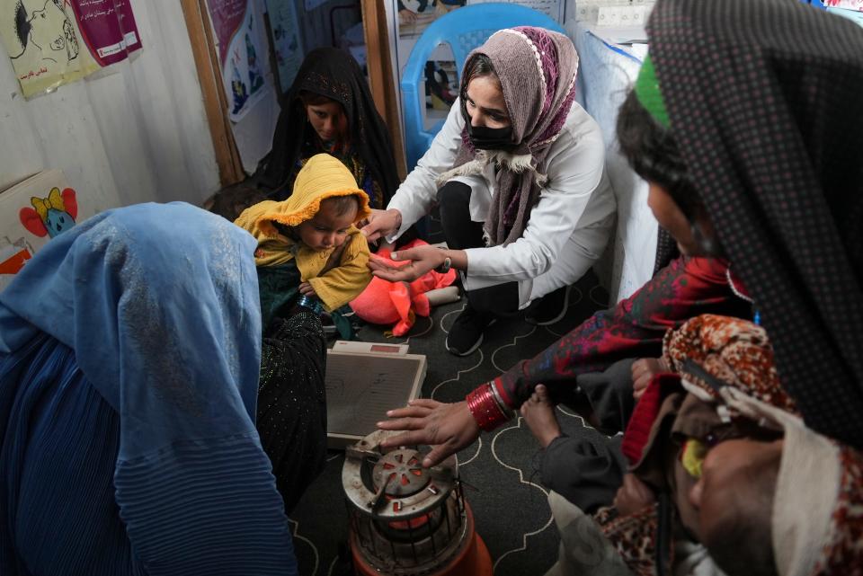 A nurse checks the weight of a child in the makeshift clinic organized by World Vision at a settlement near Herat, Afghanistan, Dec. 16, 2021.  Malnutrition stalks the most vulnerable, and aid groups say more than half the population faces acute food shortages.