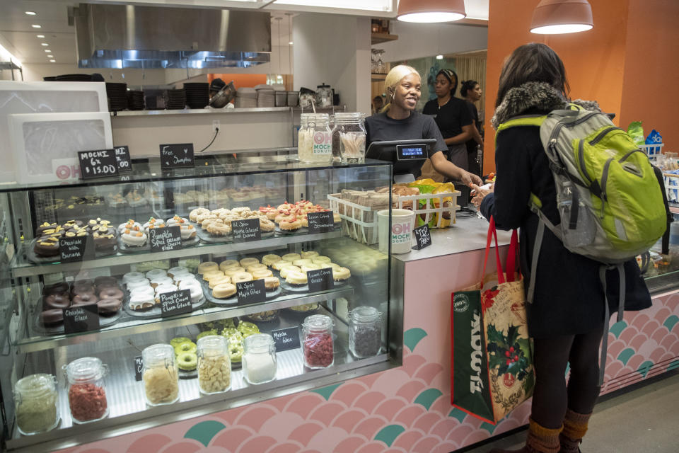 In this Tuesday, Nov. 26, 2019, photo shows a customer service representative waits on a customer Oh Mochi! donut shop at the Nordstrom NYC Flagship in New York. (AP Photo/Mary Altaffer)