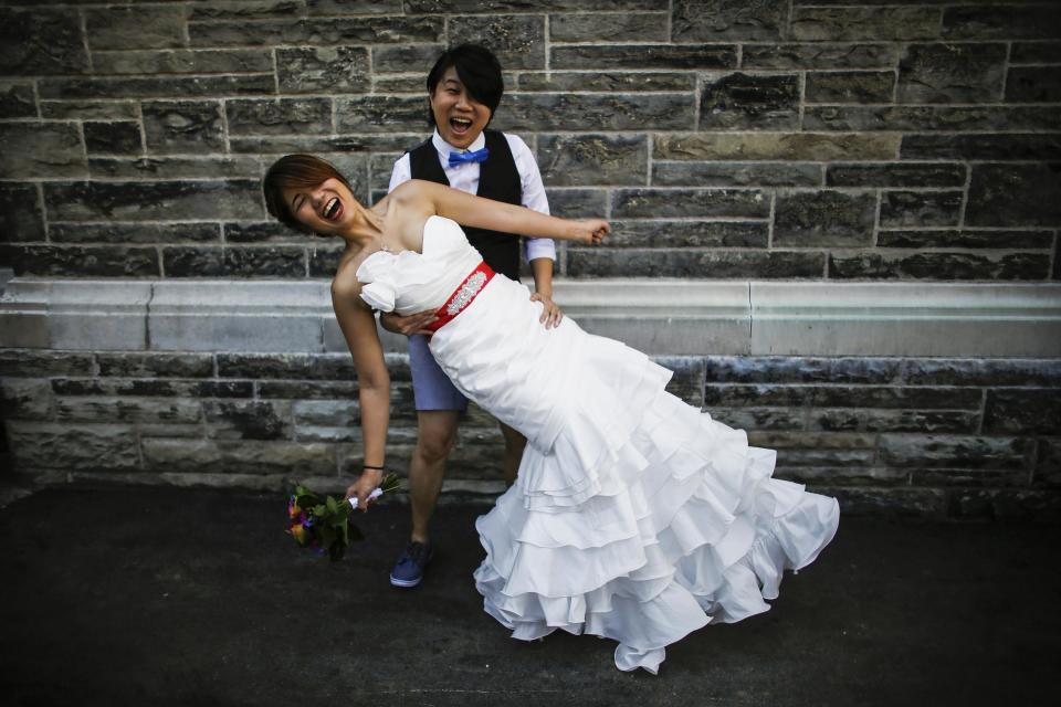 A couple poses for a picture before taking part in "The Celebration of Love", a grand wedding where over 100 LGBT couples will get married, at Casa Loma in Toronto