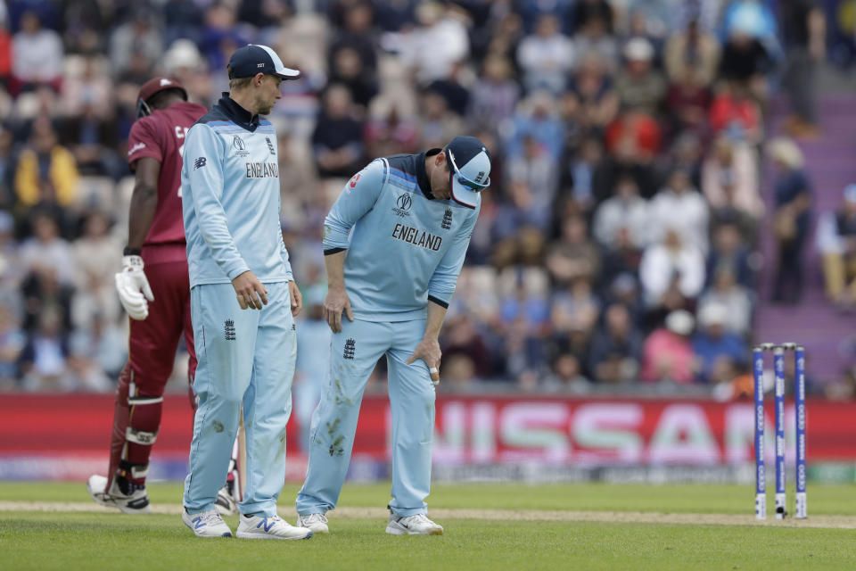 England's captain Eoin Morgan, right, hobbles off the field of play with an injury, next to England's Joe Root during the Cricket World Cup match between England and West Indies at the Hampshire Bowl in Southampton, England, Friday, June 14, 2019. (AP Photo/Matt Dunham)