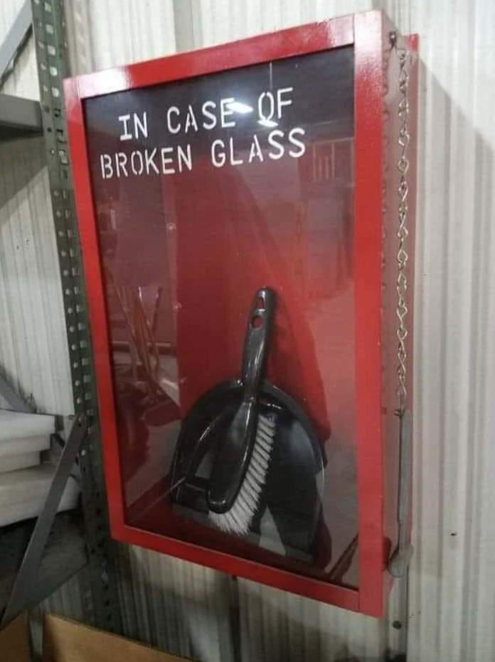 Sign reads "IN CASE OF BROKEN GLASS" with a dustpan and brush inside a red box