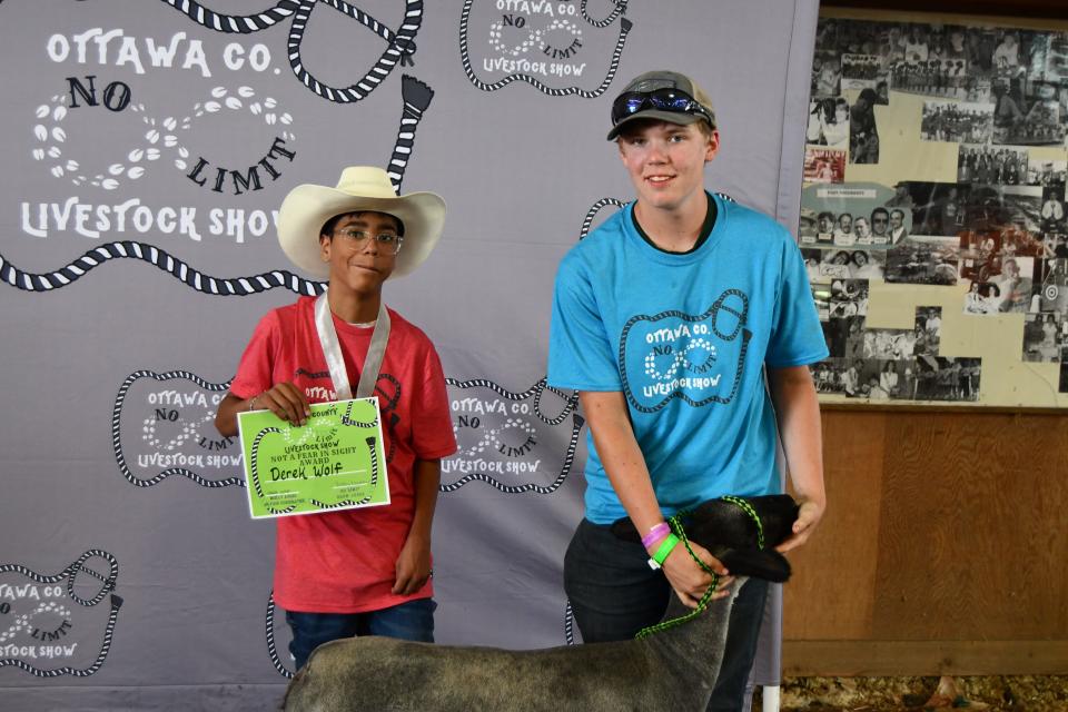 Derek Wolf, holding a certificate, entered the Ottawa County Fair No Limit Livestock Show on July 22, with a goat and with the help of mentors Josh and James Sanders.