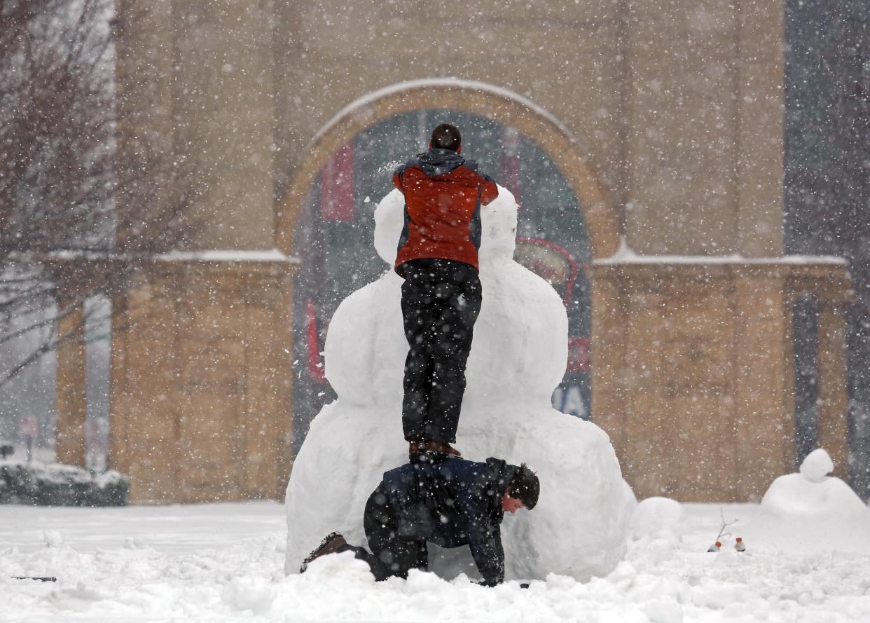 Two boys build a snowman at McFerson Commons in the Arena District in March 2015.