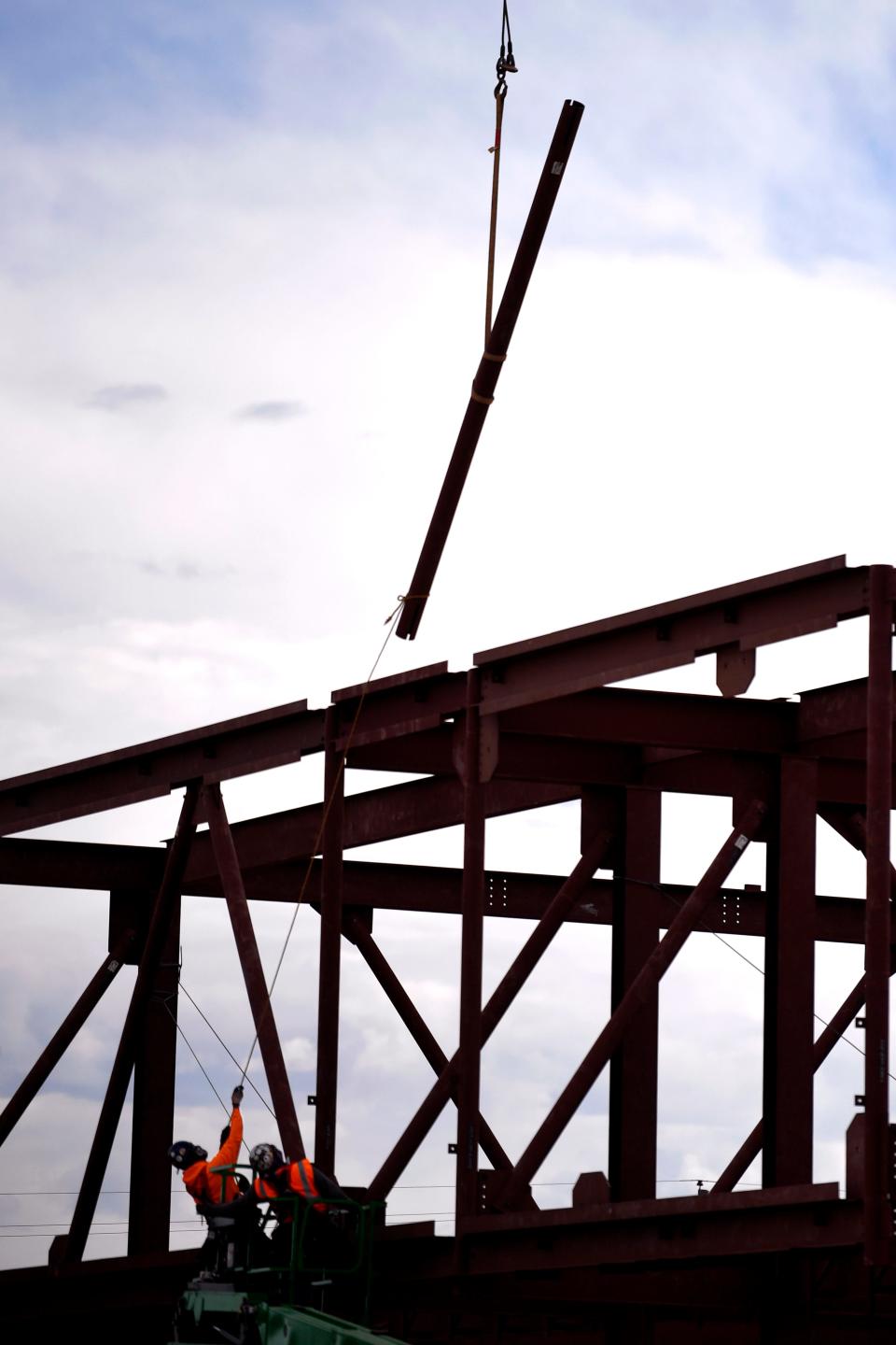 Iron workers guide a beam suspended from a crane into the skeleton of the Nuclear Energy eXperimental Testing Lab during construction at ACU Tuesday.