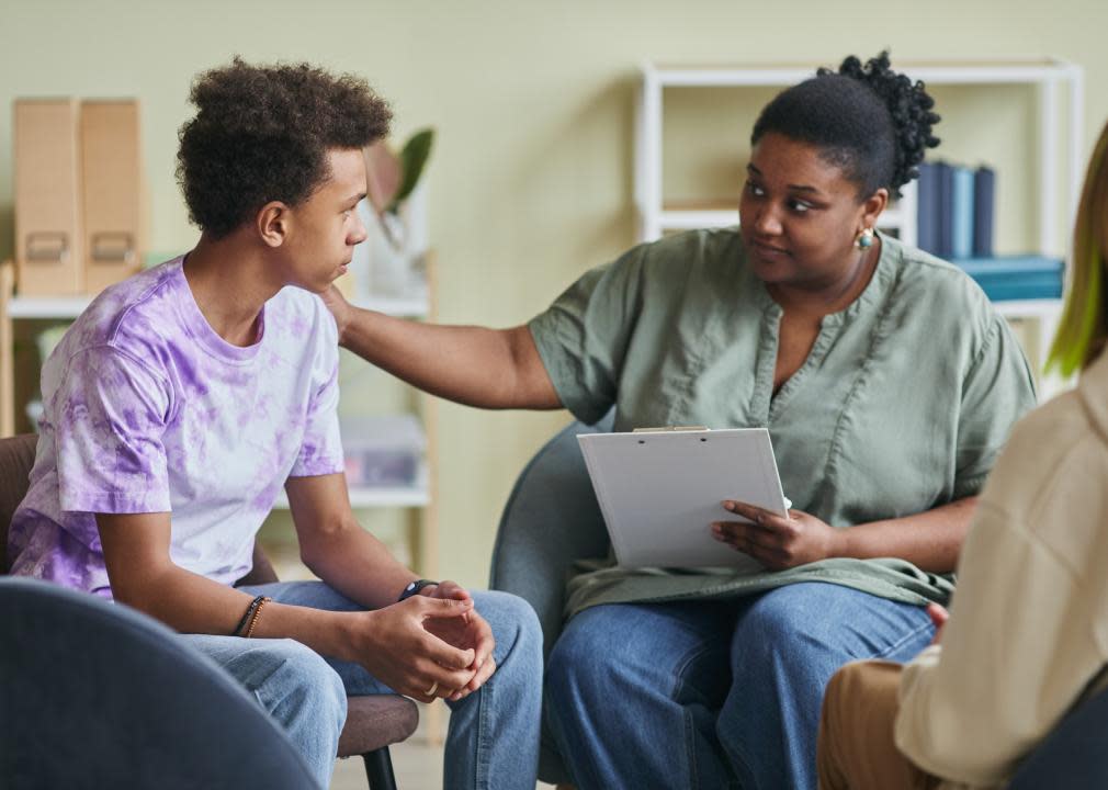 Psychologist talking to teenage boy during therapy session.