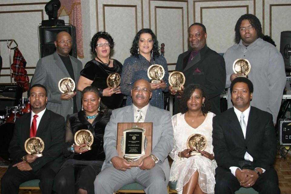 In this 2008 photo provided by the League of Martin, Lenard Wells, front row center, receives an award from an organization he led to promote the hiring of African-American officers in the Milwaukee Police Department called the League of Martin. Wells, a former Milwaukee police lieutenant and a mentor to many in the black community, died of the new coronavirus. (Kim Robinson/League of Martin via AP)