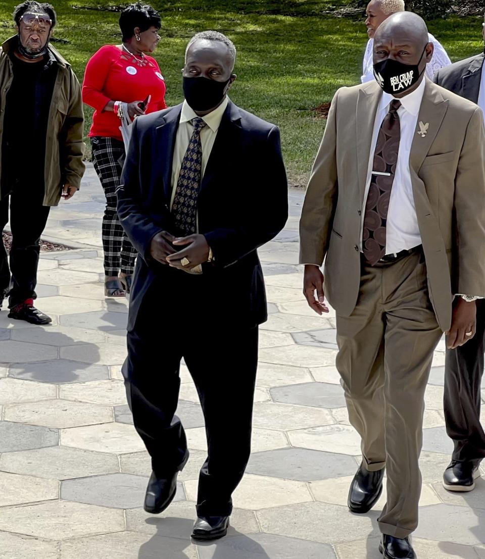 Ahmaud Arbery's father Marcus Arbery heads into the Glynn County Courthouse in Brunswick, Ga with his attorney Benjamin Crump on Monday, Oct. 18, 2021. Jury selection got underway with hundreds of people ordered to report for what could be a long, laborious effort to find jurors to hear the trial of three white men charged with fatally shooting Ahmaud Arbery as he was running in their neighborhood. (AP Photo/Lewis M. Levine)