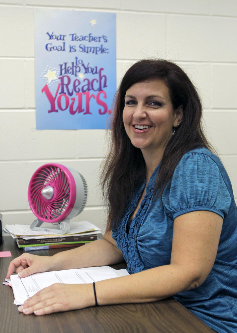 In this Friday, March 16, 2012 photo, Dawn Meehan, a teacher's assistant and writer, sits at her desk in her classroom at Gotha Middle School in Windermere, Fla. Meehan, 42, had a colonoscopy in February 2012, under deep sedation monitored by an anesthesia specialist; her insurance covered everything. Colonoscopies to screen for colon cancer usually aren't recommended until age 50 but Meehan had the exam because of symptoms for a common digestive disease. She was a low-risk patient and said if her colonoscopy doctor had offered it, she might have chosen light sedation. But even though the extra sedation is more costly, Meehan said patients who want it should get it, because otherwise some might "shy away from getting screened." (AP Photo/John Raoux)