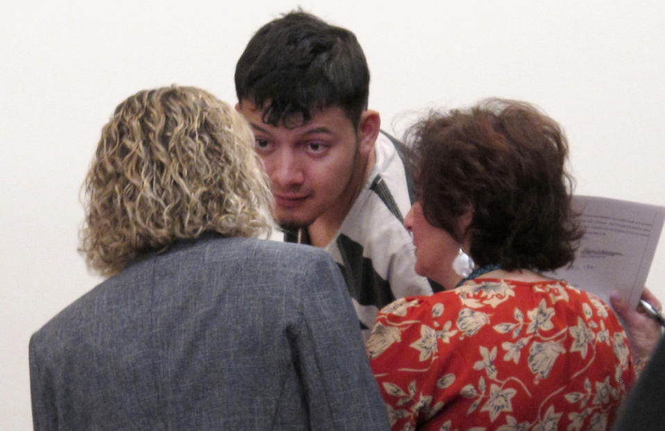 Wilber Ernesto Martinez-Guzman, 19, of El Salvador, listens to his public defender and interpreter during his initial appearance in Carson City Justice Court, Thursday, Jan. 24, 2019, in Carson City, Nev. Martinez-Guzman was arraigned on 36 felonies including two dozen weapon charges. He's a suspect in a series of four homicides earlier this month in Reno and south of Carson City in rural Gardnerville. Prosecutors say additional charges are pending. (AP Photo/Scott Sonner)