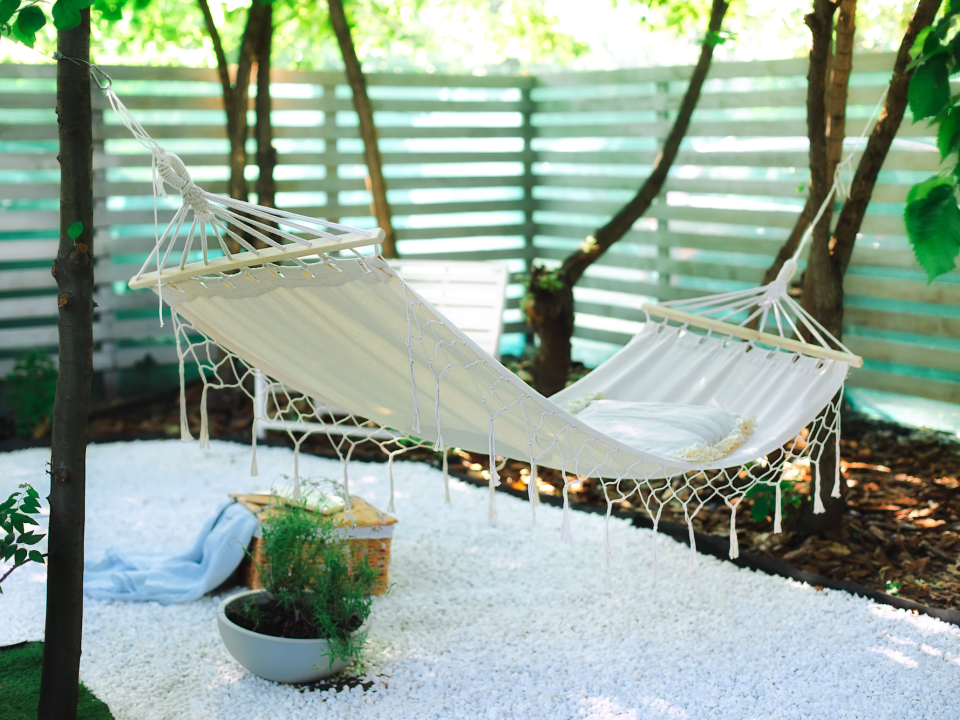 white boho Hammock hanging on tree in summer garden.