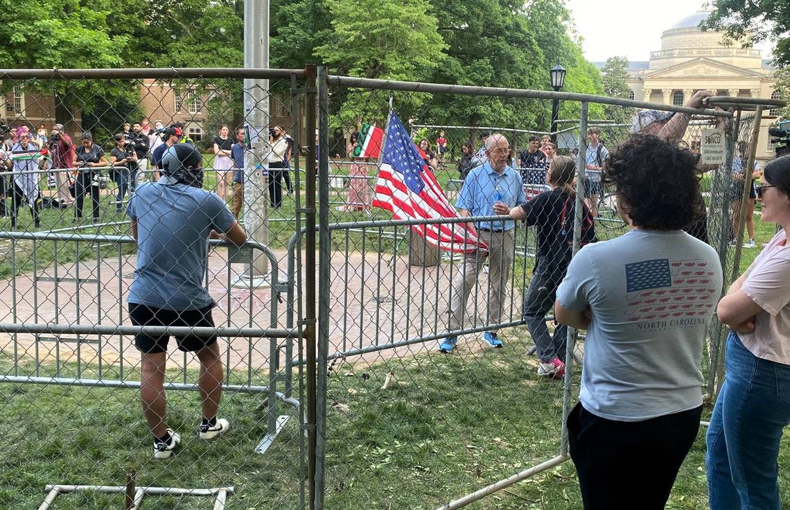 An unidentified man stands with a U.S. flag that he brought to UNC’s Chapel Hill campus on Tuesday evening after the official flag was taken down from the flagpole twice. Protesters briefly replaced the U.S. flag with a Palestinian flag.