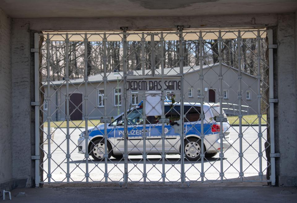 A police car guards behind the closed camp entrance with the slogan 'To Each His Own' (Jedem das Seine) at the 75th anniversary of the liberation of the former Nazi concentration camp Buchenwald by the US Army near Weimar, Germany, Saturday, April 11, 2020. Because of Corona crisis, the memorial is currently closed and all commemoration ceremonies with survivors have been cancelled. For most people, the new coronavirus causes only mild or moderate symptoms, such as fever and cough. For some, especially older adults and people with existing health problems, it can cause more severe illness, including pneumonia. (AP Photo/Jens Meyer)