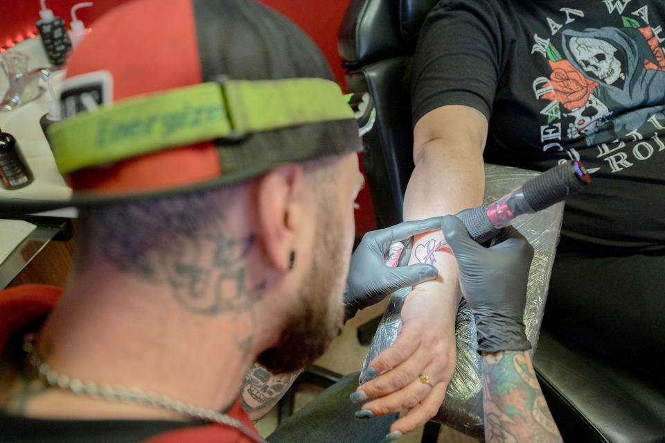 Michael Preston applies a memorial tattoo on the arm of Kim Beeman using her late daughter Amelia Gutierrez' ashes mixed with the ink on Wednesday.