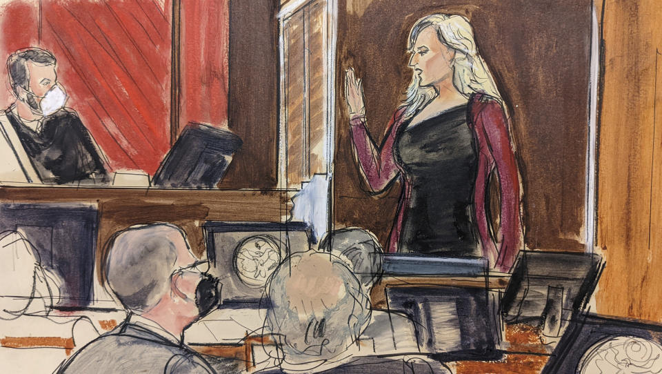 In this courtroom sketch, Stormy Daniels, right, stands while being sworn in by Judge Jesse Furman, upper left, as Michael Avenatti faces her, lower left, in federal court, in New York, Thursday, Jan. 27, 2022. Daniels took her star turn on the witness stand Thursday at California lawyer Michael Avenatti's trial, telling a jury Avenatti "stole from me and lied to me." (AP Photo/Elizabeth Williams)