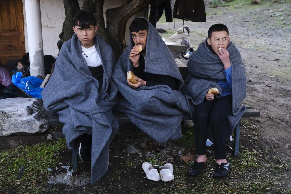 Migrants who arrived yesterday to Greece from Turkey eat bread as they try to warm themselves at the village of Skala Sikaminias, on the Greek island of Lesbos on Friday, March 6, 2020. Thousands of refugees and other asylum-seekers have tried to enter Greece from the land and sea in the week since Turkey declared its previously guarded gateways to Europe open. (AP Photo/Alexandros Michailidis)