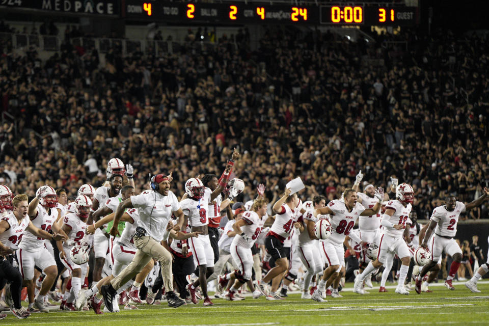 Miami (Ohio) players and coaches celebrate after a defensive back Yahsyn McKee intercepts the ball in the end zone during overtime of an NCAA college football game against Cincinnati, Saturday, Sept. 16, 2023, in Cincinnati. (AP Photo/Jeff Dean)