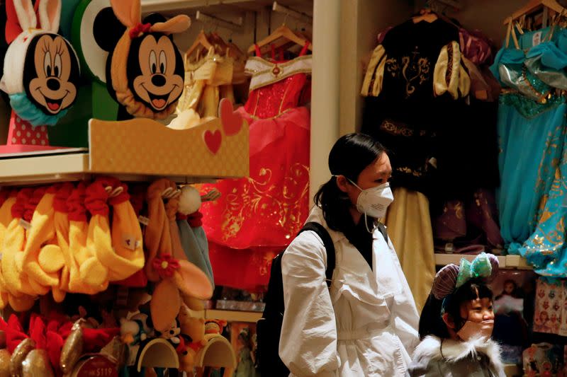 FILE PHOTO: A child wears mask as she trying a themed ears at a souvenir shop in Disneyland hotel after Hong Kong Disneyland that has been closed, following the coronavirus outbreak in Hong Kong