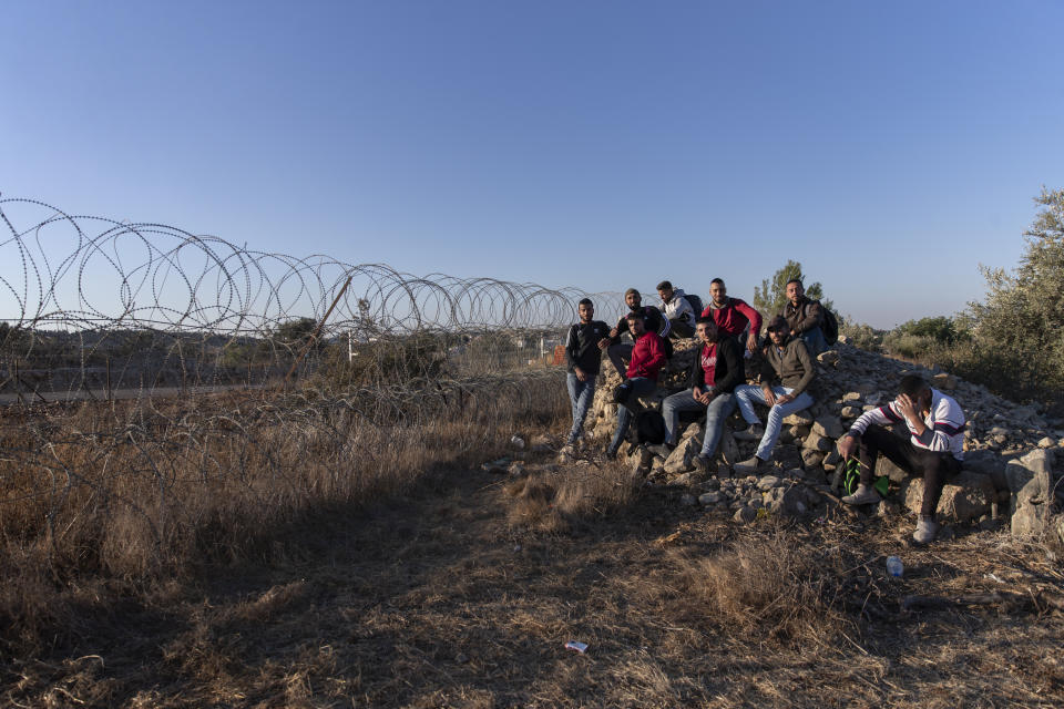 Palestinians gather by a section of Israel's separation barrier, while they wait for the Israeli army to allow them to cross the fence, in the West Bank village of Nilin, west of Ramallah, Sunday, Nov. 7, 2021. Nearly two decades after Israel sparked controversy worldwide by building the barrier during a Palestinian uprising, it has become a seemingly permanent feature of the landscape — even as Israel encourages its citizens to settle on both sides. (AP Photo/Nasser Nasser)