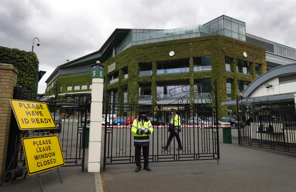 FILE - Security guards are shown at the gate in front of Centre Court at the All England Lawn Tennis Club, after the 2020 tennis championships were canceled due to the coronavirus, in Wimbledon, London, Monday, June 29, 2020. This year's Wimbledon tournament begins on Monday, July 1. (AP Photo/Kirsty Wigglesworth, File)