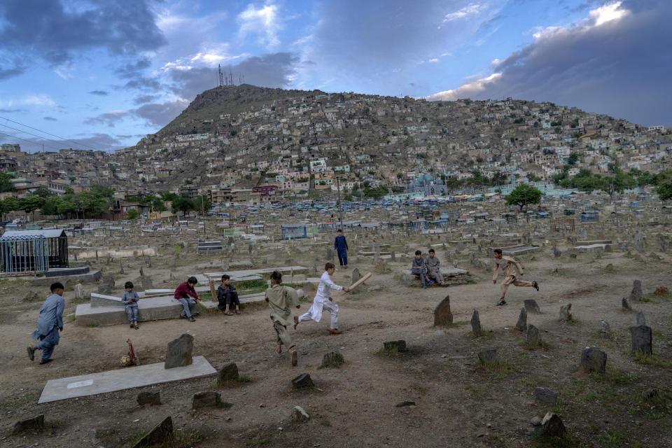 Afghan boys play cricket at a cemetery in Kabul, Afghanistan, Wednesday, May 4, 2022. There are cemeteries all over Afghanistan's capital, Kabul, many of them filled with the dead from the country's decades of war. They are incorporated casually into Afghans' lives. They provide open spaces where children play football or cricket or fly kites, where adults hang out, smoking, talking and joking, since there are few public parks. (AP Photo/Ebrahim Noroozi)