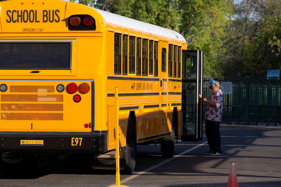 An employee waits to assist a student off a bus as in-person learning resumes with restrictions in place to prevent the spread of coronavirus disease (COVID-19) at Rover Elementary School in Tempe, Arizona, U.S., August 17, 2020.  REUTERS/Cheney Orr     TPX IMAGES OF THE DAY