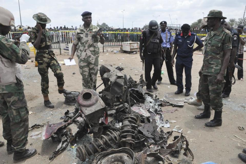 Soldiers inspect the remains of a car following an explosion at a bus park in Abuja, Nigeria, Monday, April. 14, 2014. An explosion blasted through a busy commuter bus station on the outskirts of Nigeria's capital, Abuja, before 7 a.m. (0600 GMT) Monday as hundreds of people were traveling to work. Many are feared dead. Reporters saw rescue workers and police gathering body parts. The blast ripped a hole 4 feet deep (1.2 meters) in the ground of Nyanya Motor Park about 16 kilometers (10 miles) from the city center and destroyed more than 30 vehicles, causing secondary explosions as their fuel tanks ignited and burned. (AP Photo/ Gbemiga Olamikan)