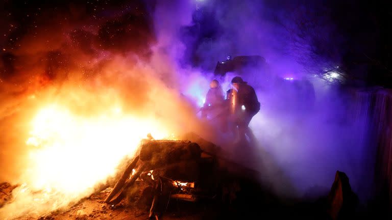 Police officers and firefighters work to the clear the way after demonstrators blocked a road