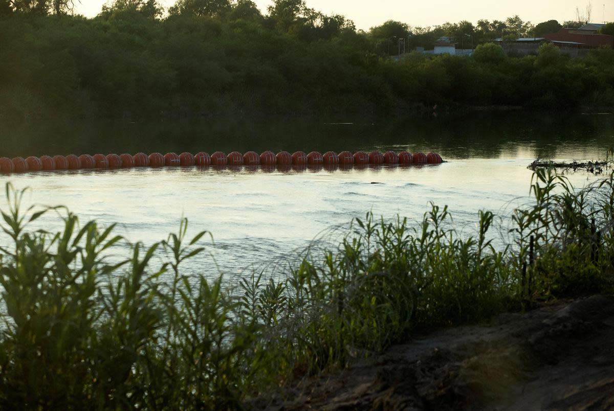 An unfinished strand of orange buoys, meant to deter migrants from crossing the river, sits in the Rio Grande near Eagle Pass on July 11, 2023.