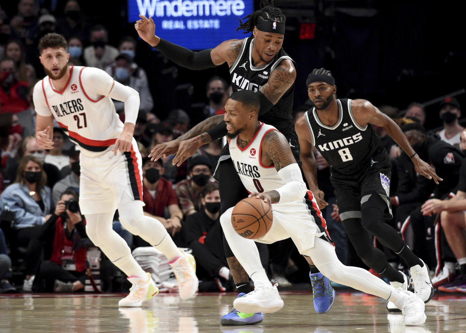 Portland Trail Blazers guard Damian Lillard, bottom, tries to get past Sacramento Kings center Richaun Holmes, top, during the first half of an NBA basketball game in Portland, Ore., Wednesday, Oct. 20, 2021. (AP Photo/Steve Dykes)