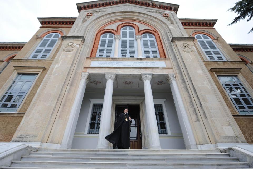 FILE - In this Aug. 3, 2013 file photo, a priest stands at the entrance of the Theological School of Halki, perched atop a hill on Heybeli Island, one of several islands off the coast of Istanbul, which closed its doors in 1971. Although shut down for some 43-years, one of the Orthodox Church's most pre-eminent seminaries on Heybeli Island, is kept in pristine condition in the hope that it may reopen one day to educate future patriarchs and clergy. (AP Photo/Emrah Gurel, File)