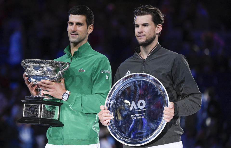 Serbia's Novak Djokovic, left, holds the Norman Brookes Challenge Cup after defeating Austria's Dominic Thiem in the final of the Australian Open tennis championship in Melbourne, Australia, Monday, Feb. 3, 2020. (AP Photo/Andy Brownbill)