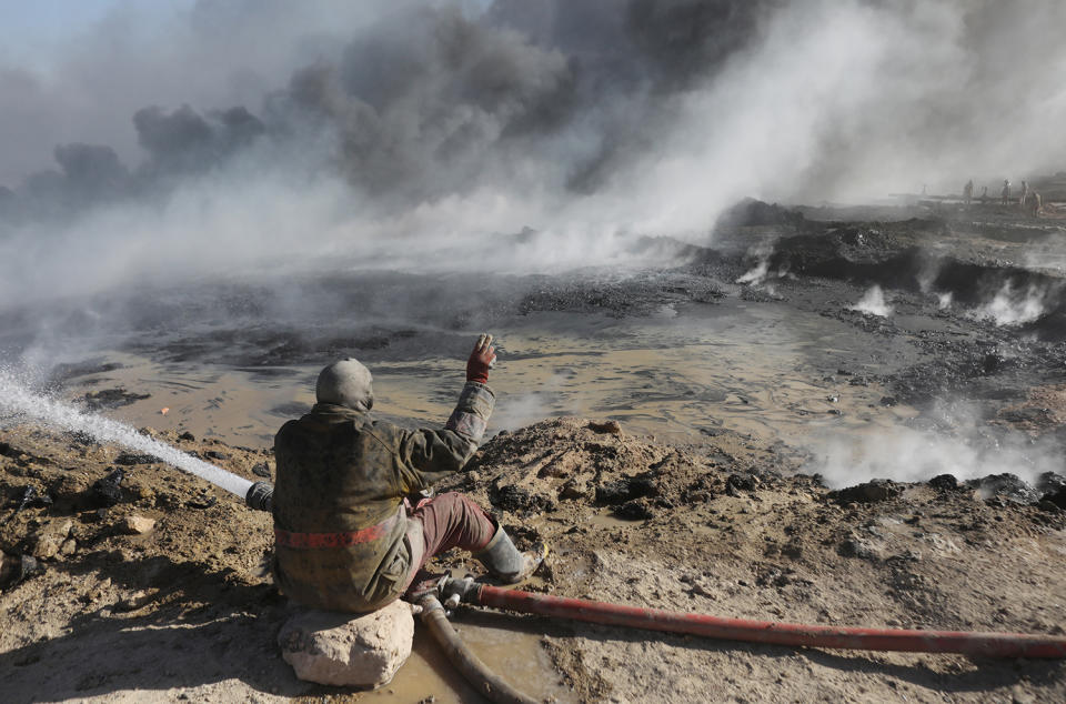 An oil worker gestures in front of oilfields burned by Islamic State fighters in Qayyara