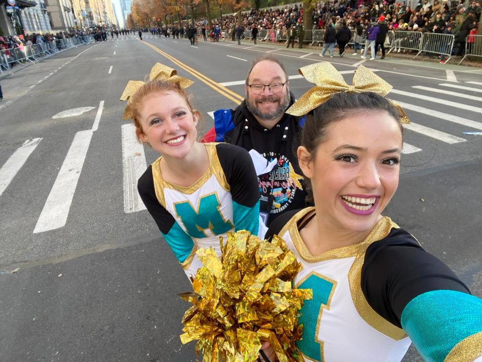 Gracie Cantrell, foreground, Josie Castle and Washington Cheer coach Jeff LeForce snap a selfie at the Macy’s Thanksgiving Day Parade.