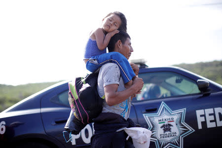 Rosendo Noviega, a 38-year-old migrant from Guatemala, part of a caravan of thousands from Central America en route to the United States, holds his daugther Belinda Izabel as he walks along the highway to Juchitan from Santiago Niltepec, Mexico, October 30, 2018. REUTERS/Ueslei Marcelino