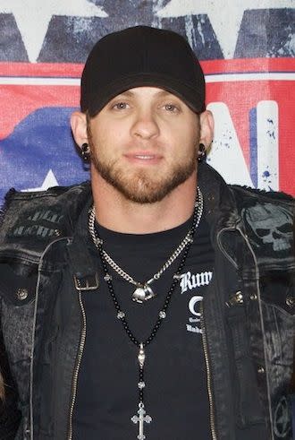 An up-close photo of Brantley Gilbert putting on denim jacket and black T