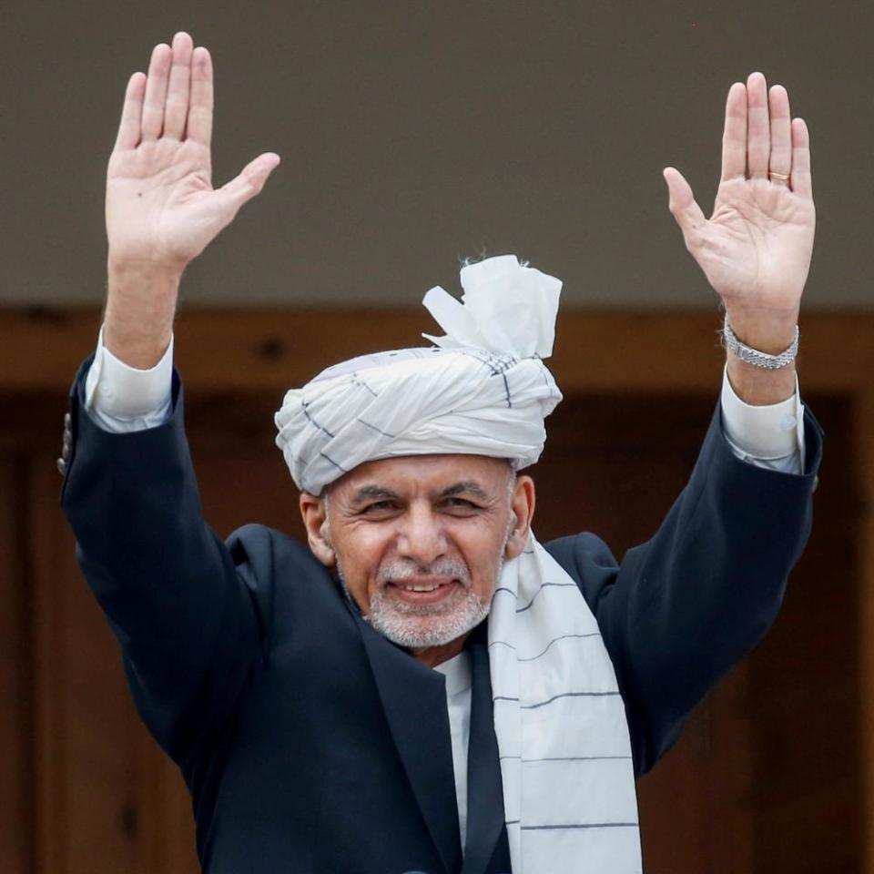 Ashraf Ghani raising both his arms to a crowd