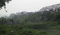 Locals and others gather around a train that derailed near Jagiroad Railway Station, about 90 kilometers (56 miles) east of Gauhati, India, Wednesday, April 16, 2014. According to a Northeast Frontier Railway officer, dozens of people were injured when the train jumped the tracks and derailed early Wednesday. (AP Photo/Anupam Nath)