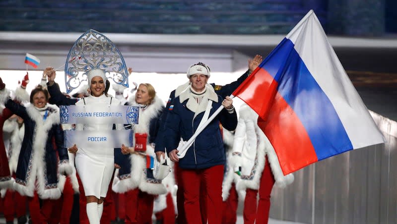 Bobsledder Alexander Zubkov carries the Russian flag next to model Irina Shayk holding the country’s identification sign at the opening ceremony of the 2014 Winter Olympics in Sochi, Russia, on Feb. 7, 2014. International Olympic Committee leaders decided Tuesday there’s no place in the Opening Ceremonies’ parade of nations for the Russian and Belarusian athletes who qualify to participate in the 2024 Summer Games in Paris.