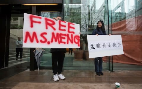 Supporters hold signs outside the British Columbia Supreme Court in Vancouver during the third day of a bail hearing for Meng Wanzhou - Credit: AP