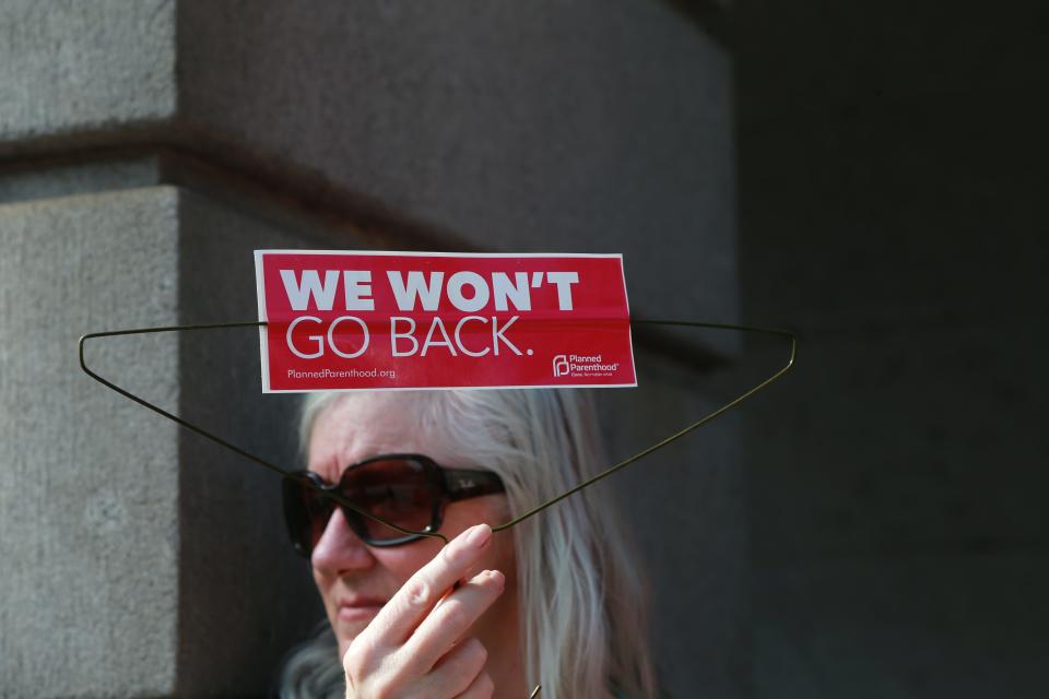An abortion-rights supporter holds a wire coat hanger with a Planned Parenthood sticker attached during a rally Tuesday evening at Savannah City Hall.