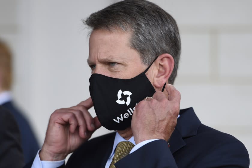 Georgia Gov. Brian Kemp adjusts his mask prior to a bill signing at Wellstar Kennestone Hospital where the hospital opened a new Emergency Room space, Thursday, July 16, 2020, in Marietta, Ga. Mayors in Atlanta and other Georgia cities deepened their defiance of Gov. Kemp on Thursday, saying they want their requirements for people to wear masks in public to remain in place, even after the Republican governor explicitly forbade cities and counties from mandating face coverings.(AP Photo/Mike Stewart)