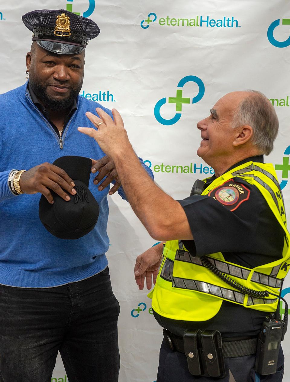 David Ortiz tries on the hat of Natick police Detective John Haswell during the retired slugger's visit Monday to the Natick Mall, Oct. 10, 2022.