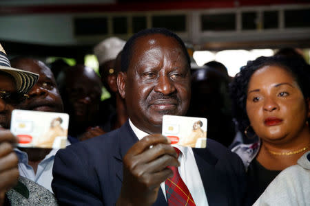 Kenyan opposition leader Raila Odinga of the National Super Alliance coalition holds a new sim card at an Airtel telecommunications shop as part of his party's campaign to boycott three big companies, including telecoms giant Safaricom, in Nairobi, Kenya November 6, 2017. REUTERS/Baz Ratner