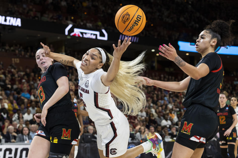 South Carolina's Victaria Saxton (5) reaches for the ball over the defense of Maryland's Faith Masonius (13) and Lavender Briggs (3) in the first half of an Elite 8 college basketball game of the NCAA Tournament in Greenville, S.C., Monday, March 27, 2023. (AP Photo/Mic Smith)