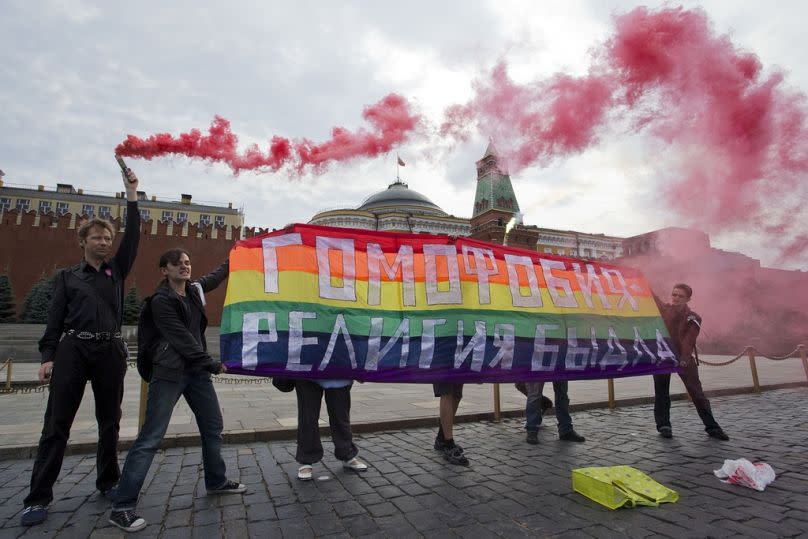 FILE - Gay rights activists hold a banner reading "Homophobia - the religion of bullies" during their action in protest at homophobia, on Red Square in Moscow, Russia, 2013.